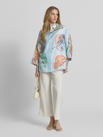 Frauenmodel trägt Bluse mit Hemdblusenkragen und 3/4-Arm von HERZENS, heller Grund mit buntem Muster, gerader Schnitt, Ganzkörperansicht von vorne.