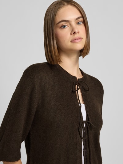 Frauenmodel trägt Regular Fit Strickjacke mit Schnürung Modell 'SIMONI' von ONLY in Dunkelbraun, strukturierte Oberfläche, Nahaufnahme Oberkörper, Damen Strickjacke von ONLY