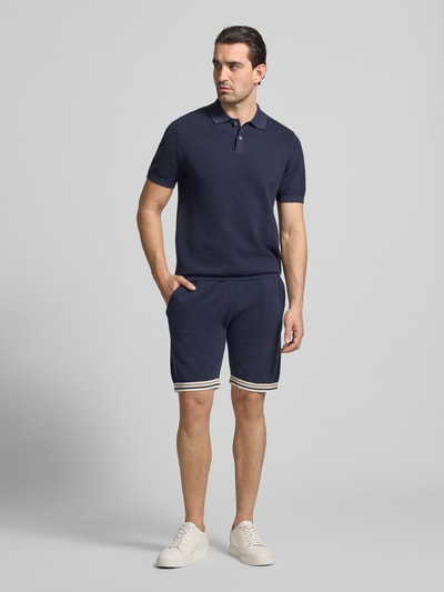 Męski model nosi Koszulka polo z fakturowanym wzorem Model 'Johan' od Christian Berg Men, bawełna, krój slim fit, krótkie rękawy, kołnierzyk polo, długość tyłu w rozmiarze M 74 cm, długość rękawów 24 cm, kolor granatowy, gładka tekstura; widok całej sylwetki z przodu.