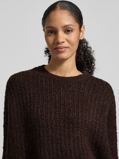 Vrouwenmodel draagt Strickpullover mit Woll-Anteil Modell 'TUMELDA' van Someday in donkerbruin, grofgebreid, ronde hals, detailopname bovenlichaam.