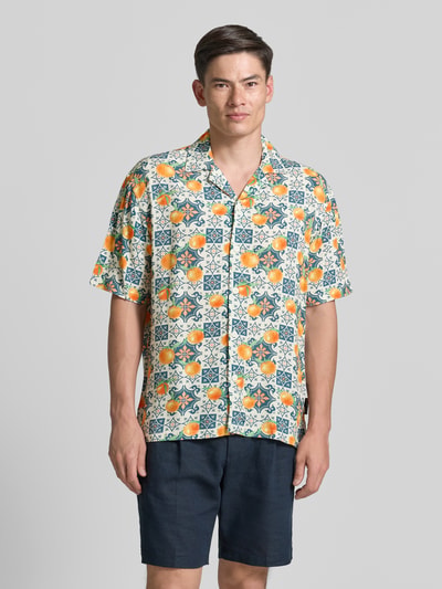 Männermodel trägt Loose Fit Freizeithemd aus reiner Viskose von Tom Tailor Denim, buntes Allover-Muster, kurzarm, Reverskragen, Ganzkörperansicht von vorne.