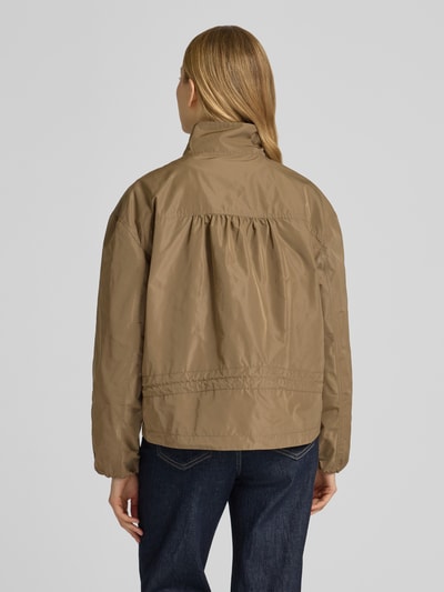 Vrouwenmodel draagt Jacke mit Zweiwege-Reißverschluss und Stehkragen van Fuchs Schmitt in beige, rechte snit, elastische boorden, productdetails volgens context, volledige lichaamsweergave achteraan.
