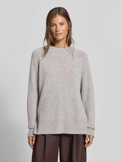 Frauenmodel trägt Regular Fit Pullover aus reinem Kaschmir in Strick-Optik von MYON, hellgrau, Rundhalsausschnitt, glatte Textur, Ganzkörperansicht von vorne.