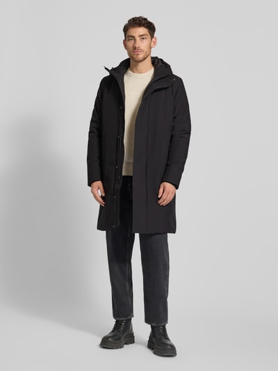 Männermodel trägt schwarzen Parka mit Kapuze Modell 'BARRY' von SAVE THE DUCK, verdeckter Reißverschluss, Ganzkörperansicht von vorne.