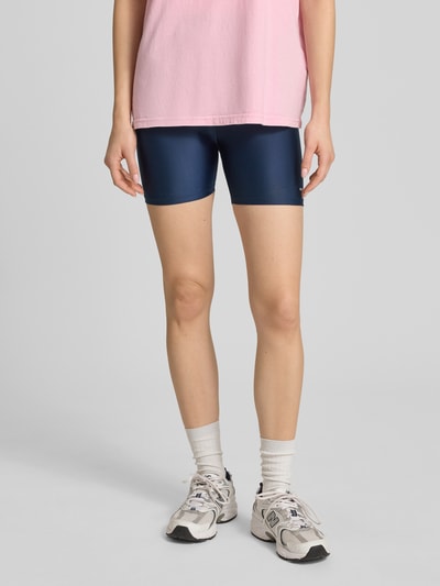 Frauenmodel trägt Slim Fit Shorts mit Logo-Print Modell 'Fairmont' von P.E Nation aus Elastischer-Material-Mix in Dunkelblau, Bundweite 28 cm, Innenbeinlänge 12 cm, Ganzkörperansicht von vorne.