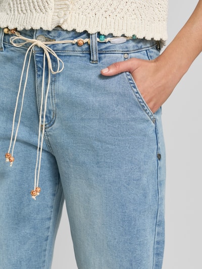 Frauenmodel trägt Barrel Fit Jeans mit Bindegürtel von Buena Vista, hellblaue Baumwoll-Mix-Jeans, sichtbare Eingrifftaschen, Nahaufnahme Oberkörper.