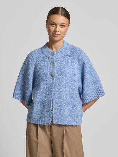 Frauenmodel trägt Strickjacke mit Knopfleiste Modell 'Benutta' von Neo Noir in Hellblau, lockerer Schnitt, gerippte Abschlüsse, Nahaufnahme Oberkörper.
