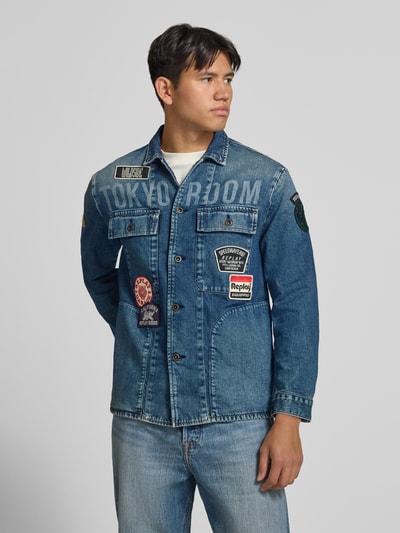 Männermodel trägt Regular Fit Jeansjacke aus Baumwoll-Mix von Replay mit Allover-Patches, blauer Denim, Nahaufnahme Oberkörper.