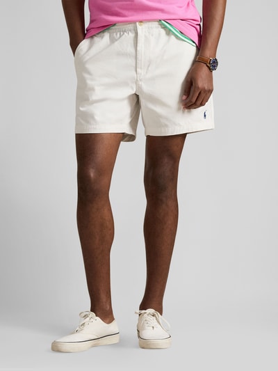 Männermodel trägt Regular Fit Shorts aus Baumwoll-Mix von Polo Ralph Lauren in Beige, unifarben mit Logo-Stitching, Ganzkörperansicht von vorne.