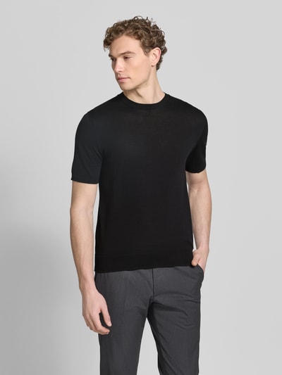Männermodel trägt schwarzes Strickshirt mit Rundhalsausschnitt von MARKUP, Regular Fit, glatte Struktur, dezentes Label-Detail, Ganzkörperansicht von vorne.