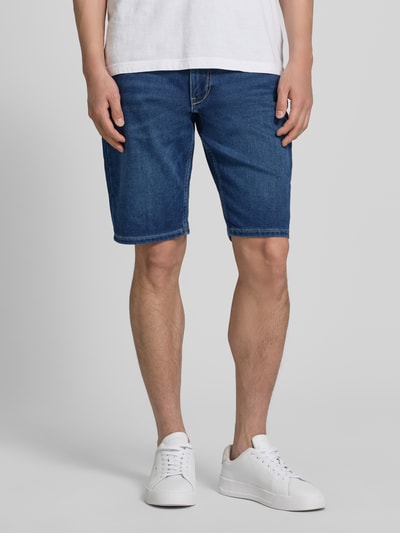 Männermodel trägt Regular Fit Jeansshorts aus Baumwoll-Mix von s.Oliver RED LABEL in Denim-Optik mit Label-Patch, Nieten, Gürtelschlaufen und 5-Pocket-Design, Ganzkörperansicht von vorne.