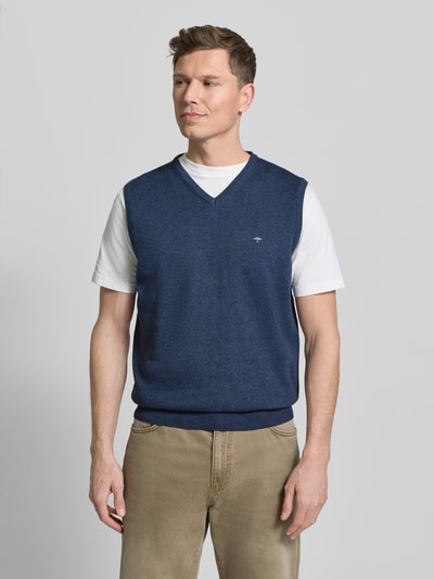 Männermodel trägt blauen Pullunder mit Label-Stitching von Fynch-Hatton, Reine Baumwolle, Regular-Fit, Gerippte-Abschlüsse, V-Ausschnitt, Rückenlänge 66 cm bei Größe M, Ganzkörperansicht von vorne.