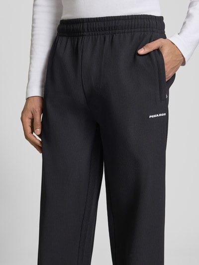 Männermodel trägt Sweatpants mit Strukturmuster und elastischem Bund von Pegador, Material-Mix mit Stretch-Anteil, Relaxed-Fit, Nahaufnahme Oberkörper.