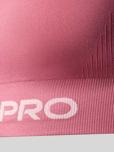 Produktfoto, Sport-BH mit Label-Bund von Nike in Rosa mit weißem Schriftzug, feine Rippstruktur, Kontext: Damen Sport-BH von Nike Training