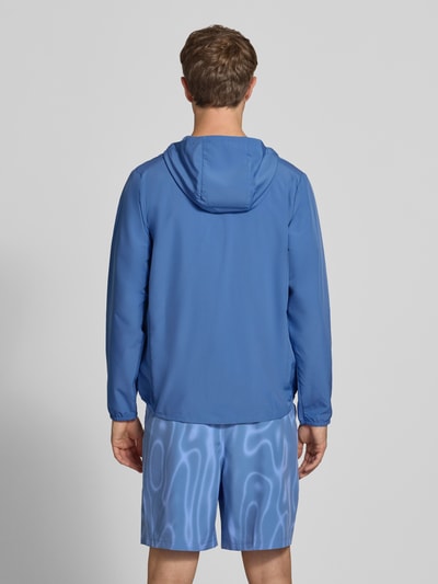 Männermodel trägt Regular Fit Trainingsjacke mit Kapuze von Nike in Blau, glatte Struktur, Herren Trainingsjacke, Ganzkörperansicht Rückansicht.