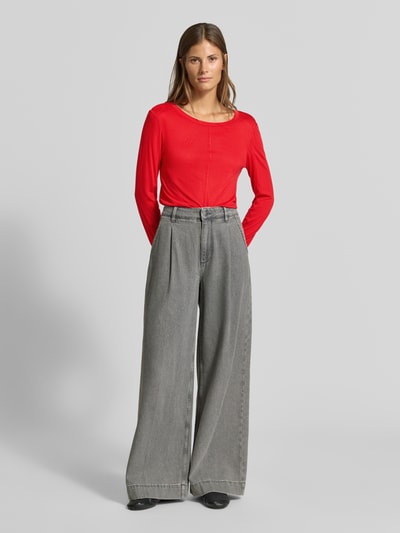 Frauenmodel trägt Longsleeve in semi-transparenter Optik von MYON, leuchtend rot, tailliert, Lyocell-Mix mit Woll-Anteil, Rundhalsausschnitt, Ziernaht, Ganzkörperansicht von vorne.