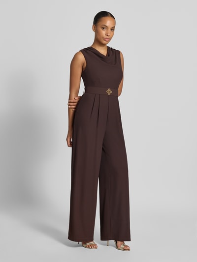 Frauenmodel trägt Jumpsuit mit Neckholder von Rinascimento, brauner Material-Mix mit Stoffgürtel, taillierte Passform, Ganzkörperansicht von vorne.