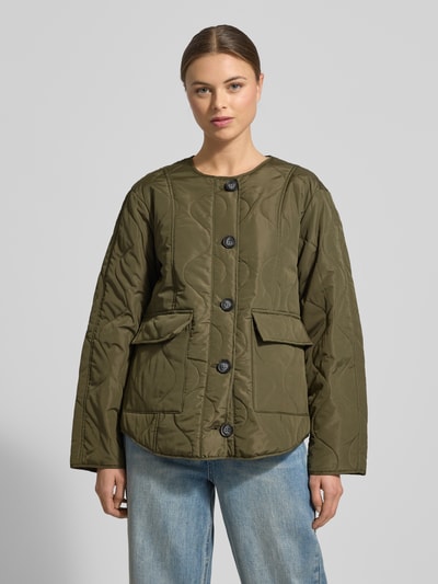 Modelka kobieca nosi Regular Fit Steppjacke mit Pattentaschen Modell 'MILLIE' od Vero Moda, efekt: jednolity kolor, krój regular fit, bez kołnierza, listwa guzikowa, długi rękaw, kieszenie z patką, wykończenie materiału: pikowanie, zdjęcie całej sylwetki z przodu.