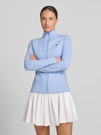 Vrouwenmodel draagt Slim Fit trainingsjack met logo-patch van Lacoste in effen kleuren, jersey, met ritssluiting en zijzakken, ultra-dry™-technologie, opstaande kraag, lange mouw, voorkant totaalbeeld