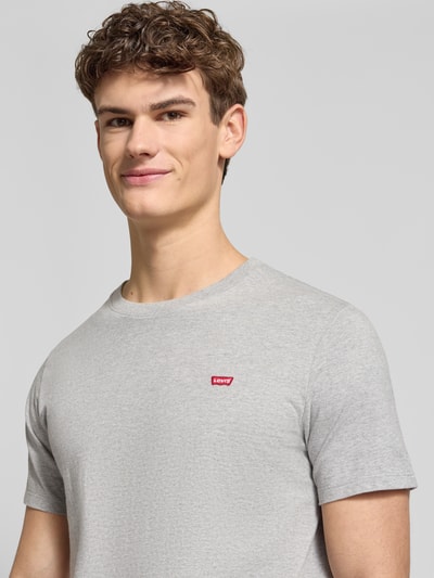 Männermodel trägt T-Shirt mit Label-Detail von Levi's®, reine Baumwolle, Regular-Fit, gerippter Rundhalsausschnitt, Nahaufnahme Oberkörper.