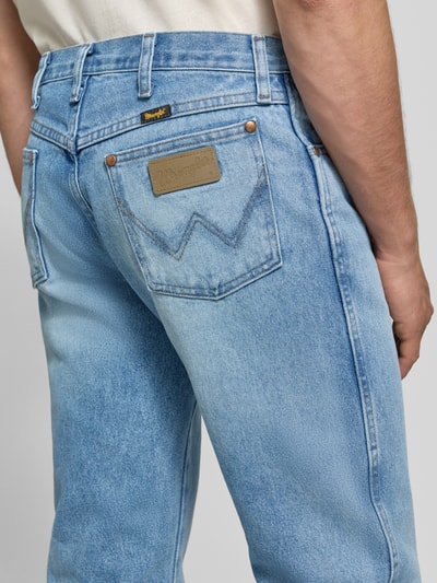 Männermodel trägt Bootcut Jeans aus reiner Baumwolle von Wrangler, denim w stylu bootcut, naszywka z logo, 5 kieszeni, szlufki, zapięcie na guzik i zamek błyskawiczny, splot twill, tył spodni, detal, Ganzkörperansicht Rückansicht