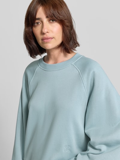 Frauenmodel trägt Oversized Sweatshirt mit Rundhalsausschnitt von Closed in hellem Blau, reine Baumwolle, Ballonärmel, Nahaufnahme Oberkörper.