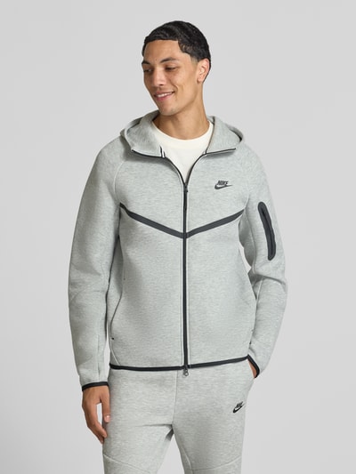 Männermodel trägt Regular Fit Sweatjacke aus Baumwoll-Mix von Nike in Hellgrau mit schwarzen Details, Ganzkörperansicht von vorne. Herren Sweatjacke von Nike