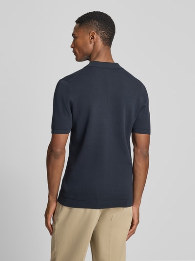 Männermodel trägt Slim Fit Poloshirt Modell 'Triton' von Drykorn aus Reine Baumwolle mit Strukturmuster, Polokragen, kurzärmelig, Rückenlänge 67 cm bei Größe M, Ganzkörperansicht Rückansicht.