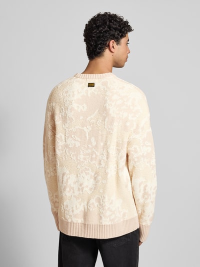 Männermodel draagt Oversized Strickpullover mit gerippten Abschlüssen van G-star, katoenmix met wol, oversized, ribboorden, ronde hals, ruglengte maat M 76 cm, mouwlengte maat M 61 cm, crèmekleurig met structuurpatroon, ganzkörperansicht rückansicht.