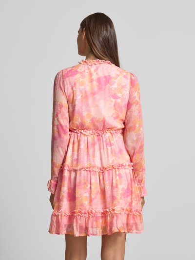 Männermodel trägt Regular Fit Sommerkleid aus Chiffon Modell 'SMILLA' von Vero Moda, różowy allover-wzór, długie rękawy, mini, krój regular fit, falbany, bez zapięcia, dekolt w serek, tekstura lekka. Ganzkörperansicht Rückansicht.