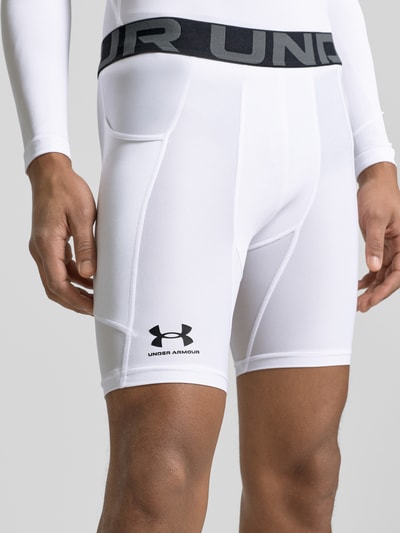 Männermodel trägt Shorts mit elastischem Logo-Bund von Under Armour in Weiß, Material-Mix mit Stretch-Anteil, Körpernaher-Schnitt, Label-Print, Bundweite 37 cm, Innenbeinlänge 21 cm, Nahaufnahme Oberschenkel.