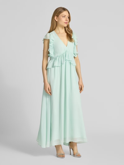 Frauenmodel trägt Cocktailkleid mit Volants Modell 'MUSSI' von YAS in fließendem Stoff mit Gerader-Schnitt als Midikleid, V-Ausschnitt; Farbe hellblau, weich fallende Textur, Ganzkörperansicht von vorne. Rückenlänge bei Größe 36: 138 cm, Brustweite: 46 cm.