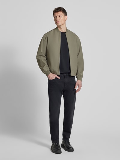 Männermodel trägt Bomberjacke mit Stehkragen Modell 'BLAASPEN' von Jack & Jones Premium, olivgrün, lockerer Schnitt, Ganzkörperansicht von vorne