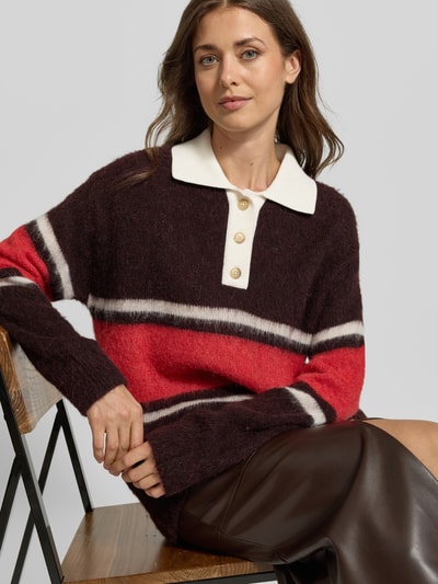 Frauenmodel trägt Strickpullover aus Woll-Alpaka-Mix von Closed, locker geschnitten, Polokragen, rot-braune Streifen, Nahaufnahme Oberkörper.