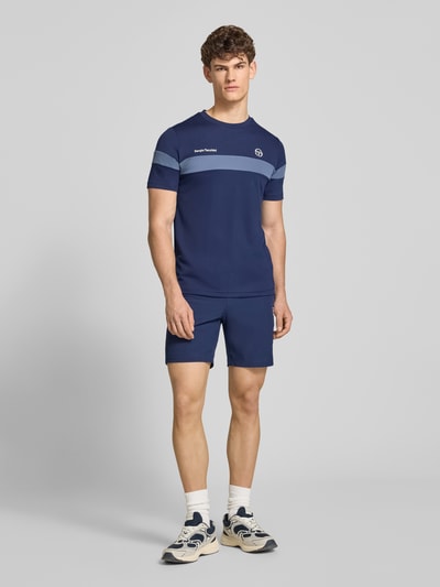 Männermodel trägt Regular Fit T-Shirt mit Logo-Print Modell 'Leone' von SERGIO TACCHINI in Dunkelblau, Ganzkörperansicht von vorne. Rundhalsausschnitt, Rückenlänge bei Größe M 71 cm, glatte Textur.