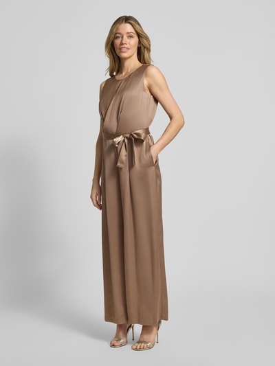 Frauenmodel trägt Shaped Fit Jumpsuit mit Taillengürtel zum Binden von s.Oliver BLACK LABEL in einfarbigem, glänzendem Satin, Ganzkörperansicht von vorne.