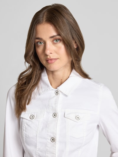 Frauenmodel trägt Jacke mit Knopfleiste und Brusttaschen von ROBE LÉGÈRE aus Baumwoll-Elasthan-Mix in Weiß, Nahaufnahme Oberkörper. Slim-Fit, Umlegekragen, Rückenlänge 41 cm, Schulterbreite 37 cm, Brustweite 45 cm, Ärmellänge 58 cm, Größe 36.