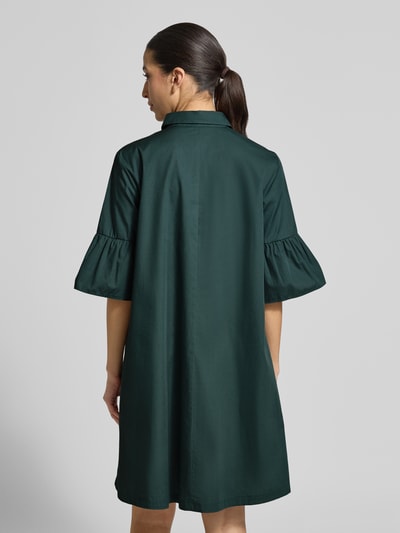 Frauenmodel trägt knielanges Hemdblusenkleid mit Kentkragen Modell 'EPOCHE' von EMME aus reiner Baumwolle, in Dunkelgrün, lockerer Schnitt, Volants, Rückenlänge bei Größe 36: 93 cm, Brustweite: 51 cm, Ärmellänge: 35 cm, Ganzkörperansicht Rückansicht.