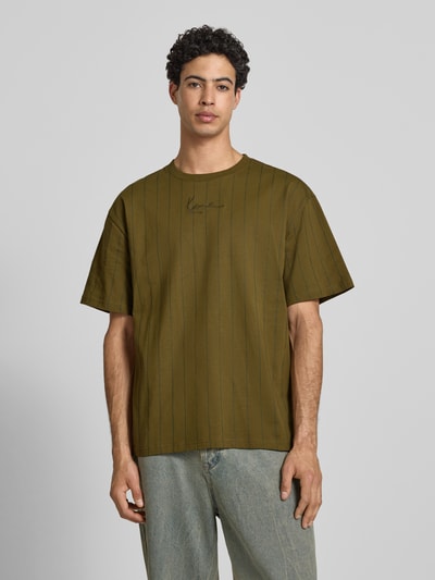 Männermodel trägt Relaxed Fit T-Shirt mit Logo-Stitching von KARL KANI in Olivgrün, reine Baumwolle, Rundhalsausschnitt, Ganzkörperansicht von vorne.