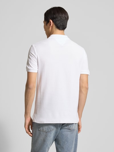 Männermodel trägt Regular Fit Poloshirt aus reiner Baumwolle von Tommy Hilfiger in Weiß, Logo-Stitching, Piqué-Struktur, Ganzkörperansicht Rückansicht.