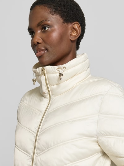 Vrouwenmodel draagt Steppjacke mit Stehkragen und Reißverschlusstaschen van Christian Berg Woman Selection, regular fit, crèmekleur, horizontale gewatteerde structuur, zijzakken met rits, detailopname bovenlichaam.