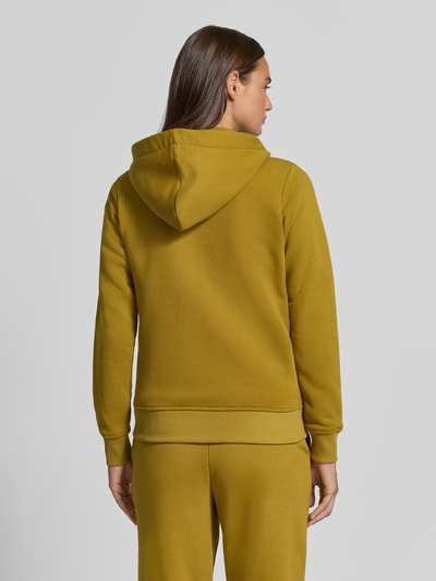 Modelka kobieca nosi Regular Fit Sweatjacke aus Baumwoll-Mix od Christian Berg Woman, mieszanka bawełny, krój regular fit, taliowany, kaptur z tunelem, oddzielna kieszeń kangurka, elastyczne wykończenia, widok całej sylwetki od tyłu.
