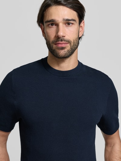 Männermodel trägt Regular Fit T-shirt aus puur katoen von MCNEAL in donkerblauw met geribde opstaande kraag en structuurpatroon, nahaufnahme oberkörper.
