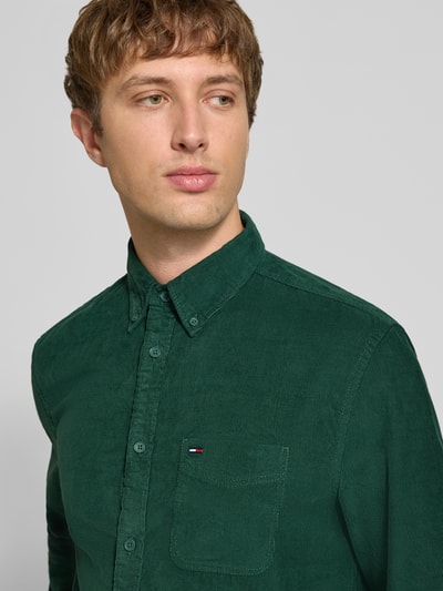 Männermodel trägt Regular Fit vrijetijdsoverhemd uit puur katoen van Tommy Jeans in effen groene kleur met structuurmotief en logodetail, nahaufnahme bovenlichaam.