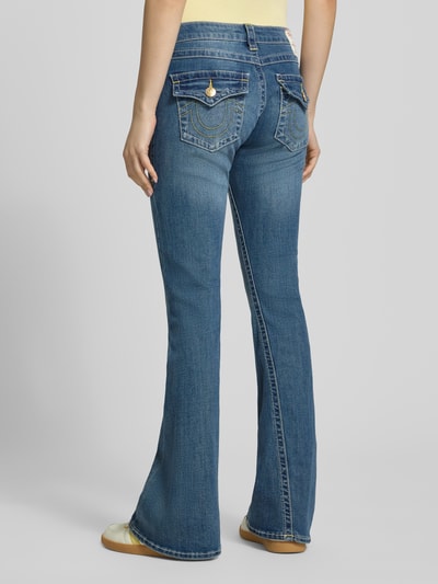 Frauenmodel trägt Low Rise Flared Jeans mit Eingrifftaschen Modell 'JOEY' von TRUE RELIGION im Used-Look, Baumwoll-Mix, Ganzkörperansicht Rückansicht.