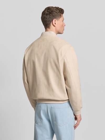 Männermodel trägt beige Bomberjacke mit Reißverschluss von REVIEW, gerippte Abschlüsse, Stehkragen, Ganzkörperansicht Rückansicht.