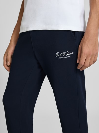 Männermodel trägt navy sweatpants met labelprint van JACK & JONES, model 'GORDON', los model, steekzakken, detailaufnahme rechterheup.