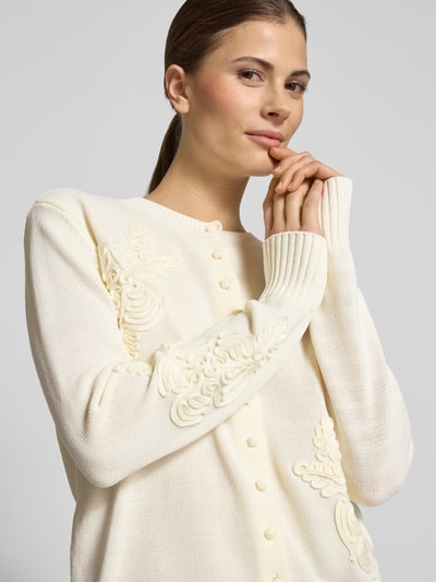 Vrouwenmodel draagt Strickcardigan met Blumen-Applikationen van Jake*s Collection in crèmekleur, katoenmix, regular fit, ronde halslijn, detailopname bovenlichaam.