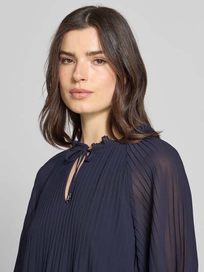 Modelka damska nosi Regular Fit Blusenshirt in Plissee-Optik od s.Oliver BLACK LABEL, efekt: jednolity kolor, okrągły dekolt, kołnierz z falbanami, wycięcie w kształcie łezki, wiązanie, krótki rękaw, plisy, krój regular fit, zbliżenie na górną część ciała