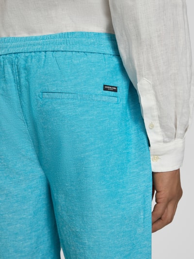 Männermodel trägt Shorts mit elastischem Bund von Scotch & Soda aus Baumwoll-Leinen-Mix in Hellblau, Detailaufnahme Rückansicht.